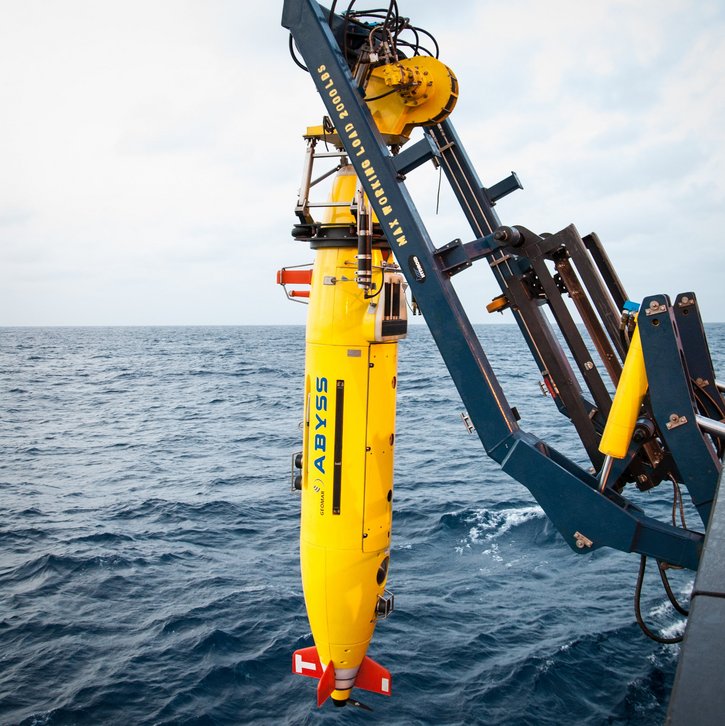 The autonomous underwater vehicle (AUV) ABYSS resembles a yellow torpedo and is suspended from a winch on the research vessel SONNE.