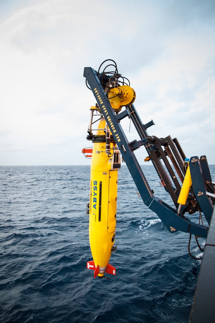 Das autonome Unterwasserfahrzeug (AUV) ABYSS sieht aus wie ein gelber Torpedo und hängt an einer Winde des Forschungsschiffs SONNE.