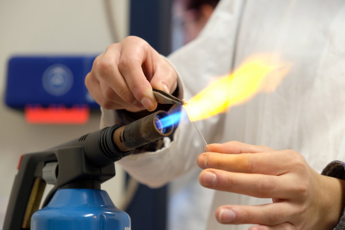 A small glass tube is formed on a burner.