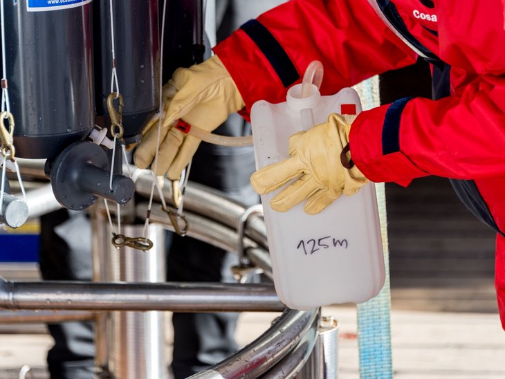 Wasser aus dem Kranzwasserschöpfer wird in einen weißen Behälter gefüllt.