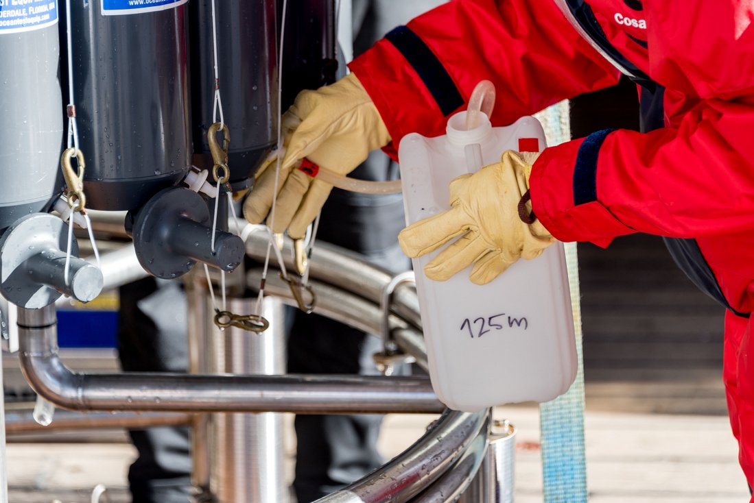 Water from the CTD Rosette Water Sampler is poured into a white container.