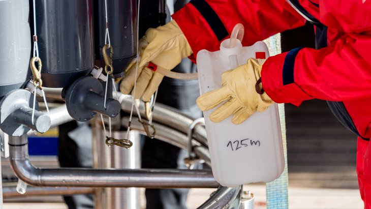 Water from the CTD Rosette Water Sampler is poured into a white container.