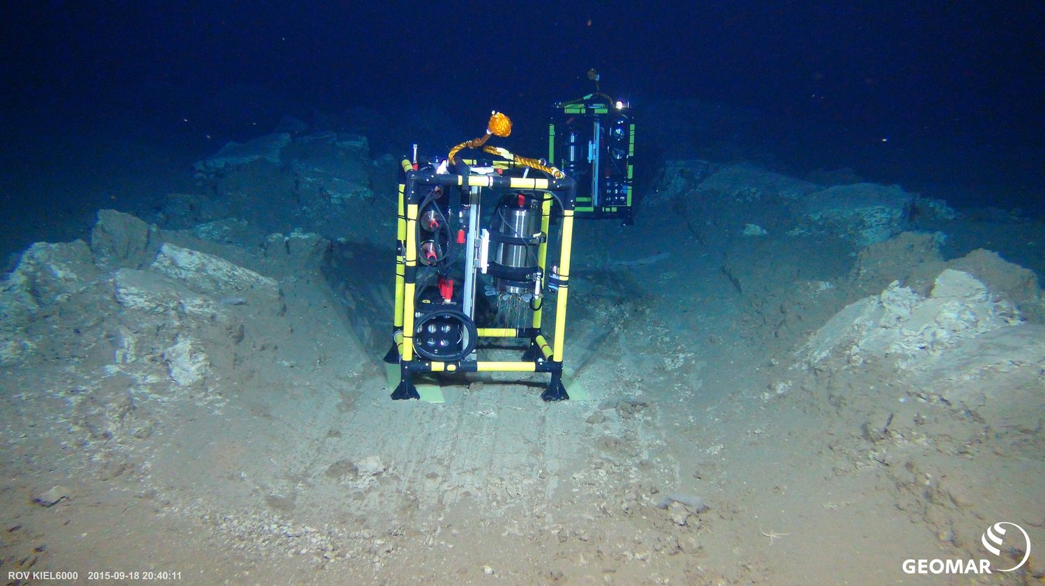 Der Mikroprofiler besteht aus einem Titangehäuse mit Sensoren und Datenerfassung, einem Motor, einer Tiefseebatterie und einem Rahmen aus gelben Stangen. Auf dem Bild steht er auf dem Meeresboden in der Tiefsee.